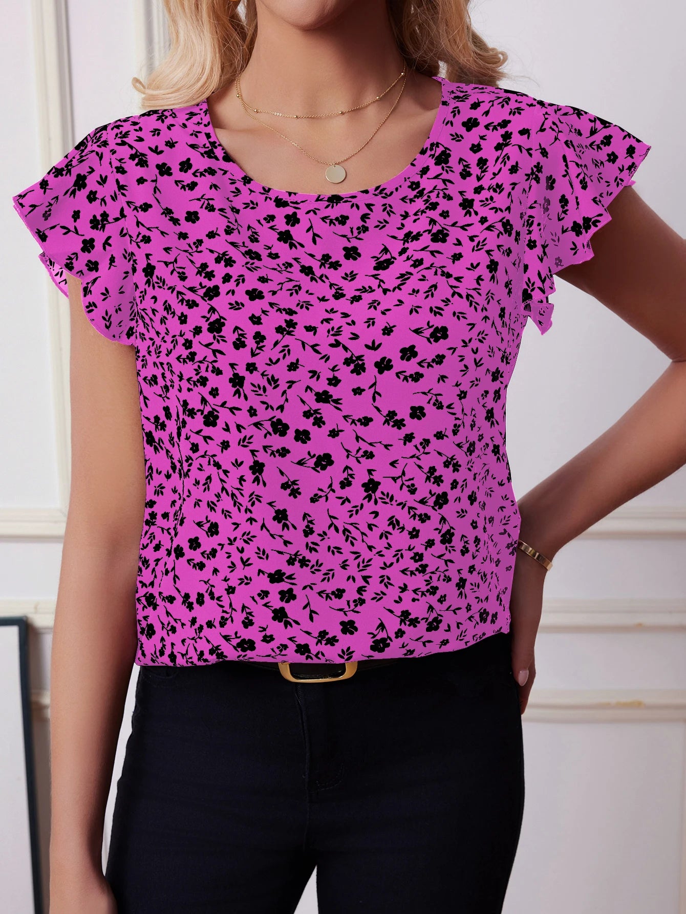Woman wearing hot pink boho floral blouse with black flower print and flutter sleeves, styled with black jeans for bold summer fashion.